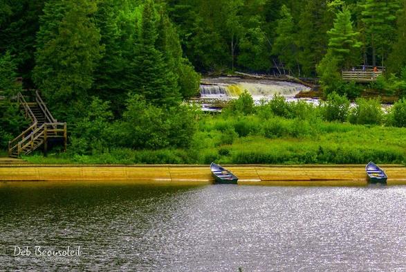 A vibrant photograph of rowboats on calm waters with the  cascading Lower Tahquamenon Falls and lush greenery in the background. Image at:  https://beautifulsunphotography.com/featured/row-boats-on-the-tahquamenon-river-deb-beausoleil.html See more art & blog at: https://beautifulsunphotography.com/ https://debbeautifulsunphotography.com/ https://www.zazzle.com/store/beautifulsun_designs https://debbeausoleil.com