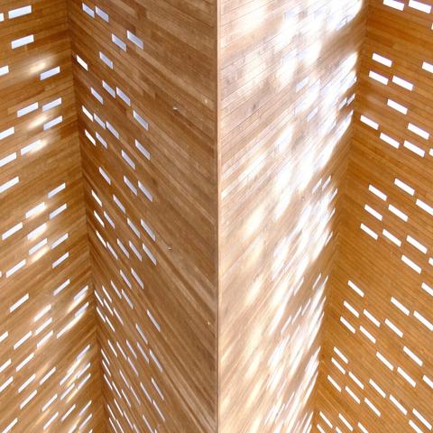 Alt text: Sunlight streaming through perforations in a wooden structure creates a pattern of light and shadow.