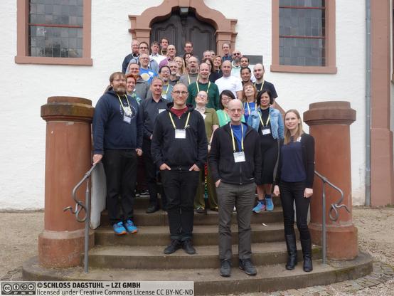 Group photo of participants of the Dagstuhl Seminar "Research Software Engineering - Bridging Knowledge Gaps" on the stairs to Schloss Dagstuhl.
