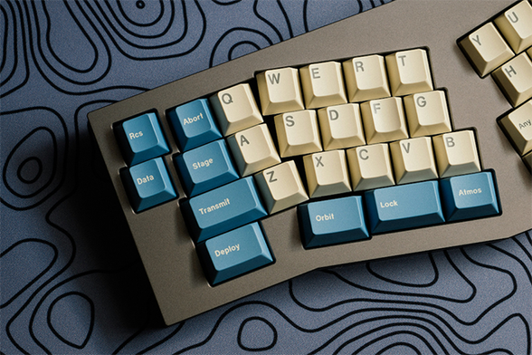 picture of the left-half of an ergonomic keyboard sitting on a gray tablecloth with black swirls printed on it