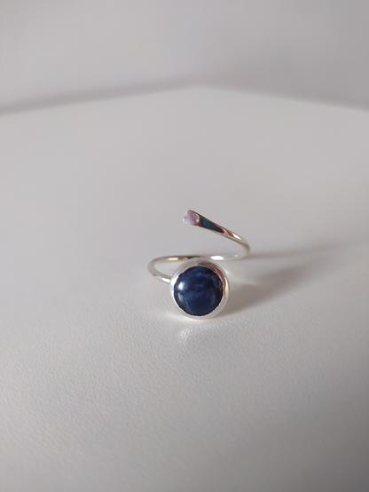 a silver open end ring with a round shaped blue gemstone