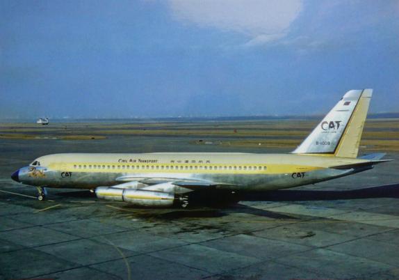 A shiny 4 engine plane with a yellow strip is parked on a ramp at Tokyo Airport. The sky is a hazy dark blue.