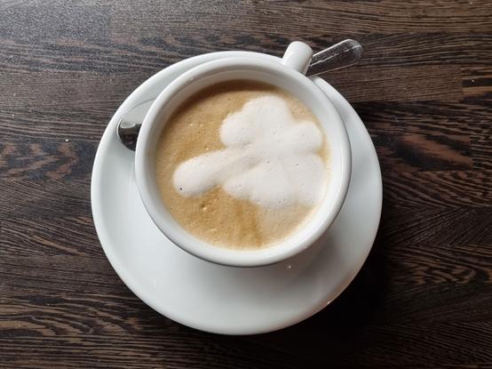 Eine Cappuccinotasse mit Milchschaum in dem ein Schmetterling zu erkennen ist.