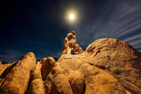 Rock formations under a night sky lit by a light source with visible stars.
