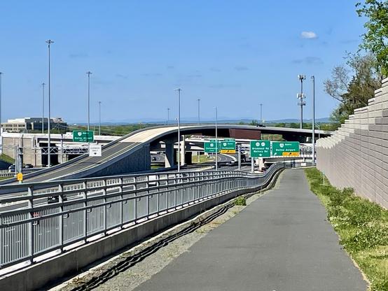 Zoomed in view of an asphalt paved trail next to a freeway with a distant mountain ridge