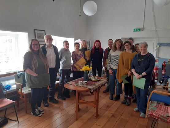 Participants in the first Climate cafe training in West Cornwall earlier this month, gathered in a circle of chairs around a small table with flowers, a candle and objects from nature.