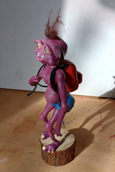 The figurine from a different angle you can see its round belly and orange backpack.