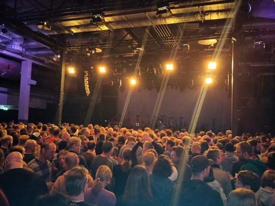 Eine Bühne und davor ein mit Blindern erhelltes Publikum. Noch keine Band auf der Bühne.