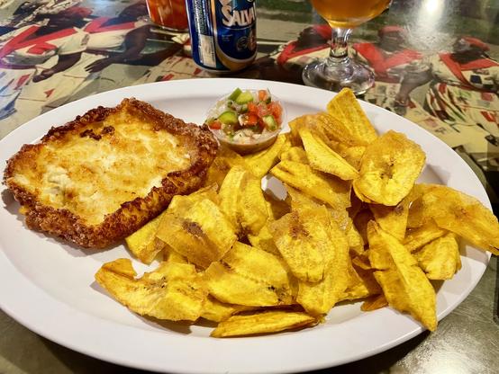 Plate in a restaurant with fried plantain chips and a baked tostada with crust and a side of pico de gallo