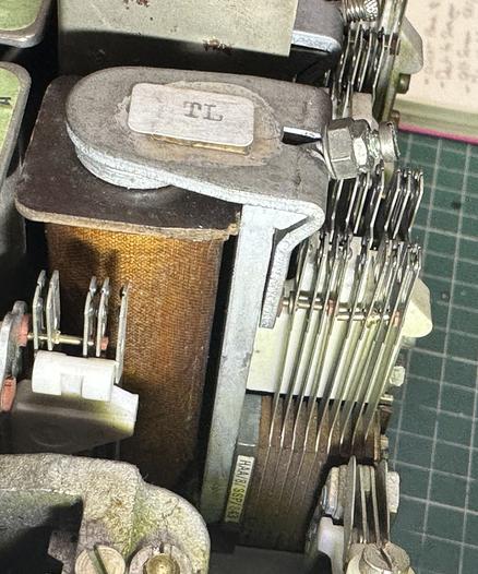 Close up of an old GPO telephone relay, a large electromagnet is in the left, a metal armature at the top, and a stack of sprung metal contacts to the right.