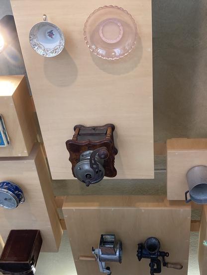 Deckenplatte, daran befestigt 1 Sammeltasse, 1 rosafarbener Glasteller, 1 alte Handkaffeemühle.