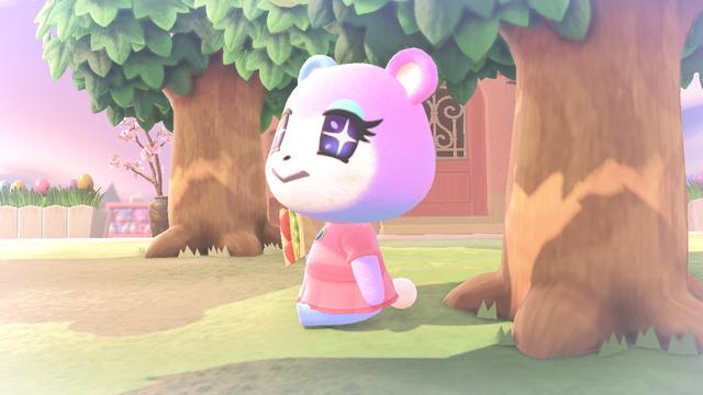 Animal Crossing: New Horizons screenshot. Taken with a soft filter, Judy (purple to blue bear cub with a Princess Peach dress and starry eyes) is sitting on the grassy ground among some trees while holding a sandwich in her right hand.