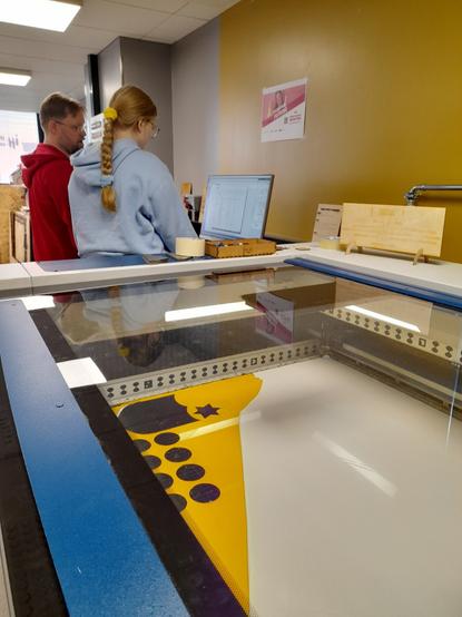 A girl and a fablab instructor setting the laser cutter