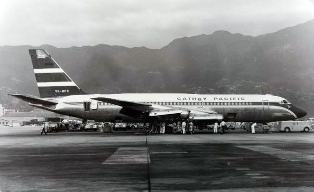 black and white photo with some mounitans in the background. ground crew are inspecting her.