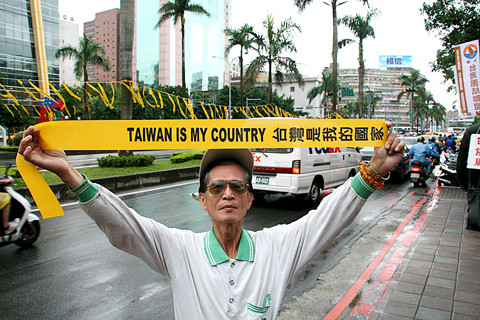 A man fearlessly holds up a banner reading "TAIWAN IS MY COUNTRY 台灣是我的國家"