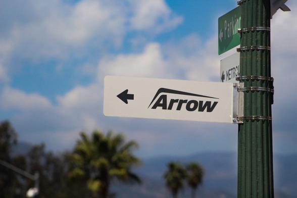 Metrolink Arrow logo on a directional sign extending from a green light pole