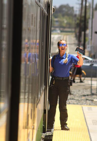 Metrolink Arrow conductor hanging out the train giving a wave and a big smile to the camera