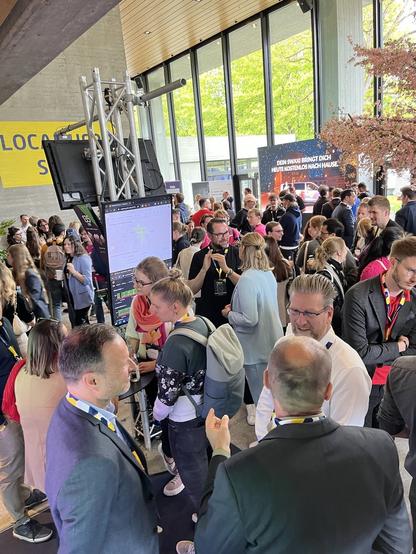 Eva Weber spricht mit Horst Thieme, dem Leiter der Geschäftsstelle Smart City am Smart City Stand der Ausstellungen im Kongress am Park. Es sind viele Menschen im Gespräch zu sehen.