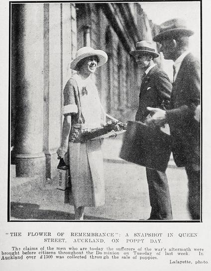 Black-and-white photo: “The Flower of Remembrance": A Snapshot in Queen Street, Auckland, on Poppy Day. The claims of the men who are to-day sufferers of the war’s aftermath were brought before citizens throughout the Dominion on Tuesday of last week. In Auckland over 1500 was collected through the sale of poppies. 1923. Description: A woman wearing a short-sleeved dress and hat stands holding a tray of poppies for sale. Two men wearing suits and hats stand in front of her; the man on the left holds a briefcase up in front of him in his left hand. Citation: Auckland Weekly News, 3 May 1923, p. 48. Auckland Libraries Heritage Collections AWNS-19230503-48-05. https://kura.aucklandlibraries.govt.nz/digital/collection/photos/id/237254
