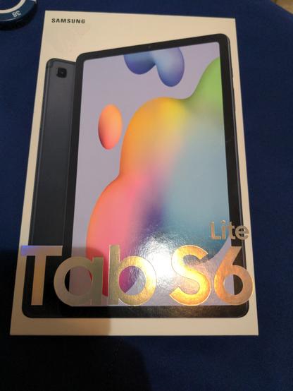 The box of a Samsung Galaxy Tab S6 Lite tablet. The tablet pictured has a fuchsia background, with rainbow blobs on it.