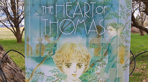 The Heart of Thomas by Moto Hagio, translated by Rachel Thorn, English hardcover a pastel-colored illustration of two boys outside a boarding school among the trees.