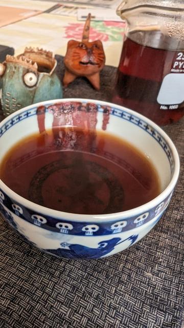 Ripe puerh in a bowl as tea pets look on.