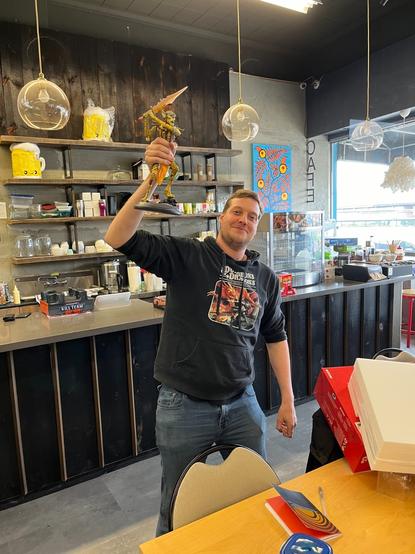 Dungeon Master Neil stands at the DND table holding up the Githyanki statue he won in the raffle at the 50th anniversary event on Saturday