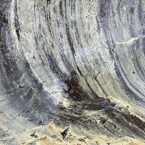 detail of the surface of a puddle. partly covered in yellow pollen gentle wind has created some wave like textures