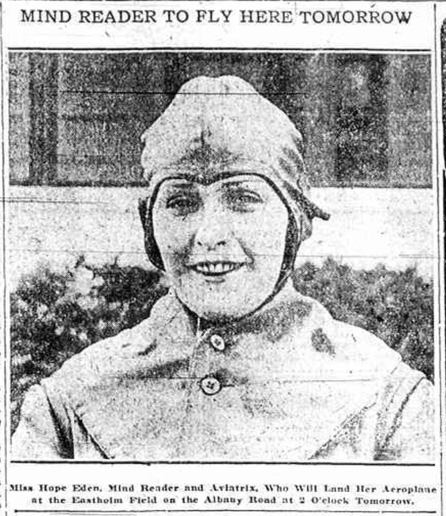 A 1919 newspaper photograph of a woman in flying gear, with a full head cover and heavy jacket buttoned up to the neck. She is looking directly at the camera, a bit of a smile on her face. The photo is scanned from a newspaper and is very low quality. The cutline above the photo says "Mind Reader to Fly Here Tomorrow." Here was Schenectady, New York. The caption reads "Miss Hope Eden, Mind Reader and Aviatrix, Who Will Land Her Aeroplane at the Eastholm Field on the Albany Road at 2 o'clock Tomorrow."