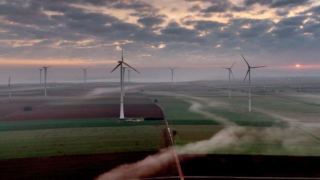 View over a wide open landscape under a dramatic sky, dotted with windmills