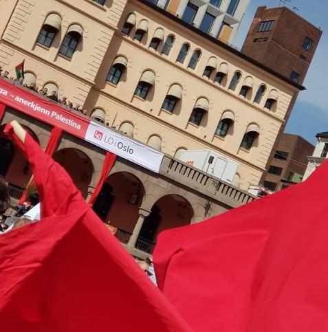 REAL photograph from May Day 2024 in Oslo, Norway. Red banners in the foreground, buildings at the Youngstorget in the background.