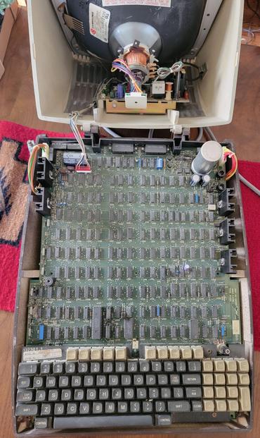 Inside a computer monitor terminal, a large exposed circuit board on a table.