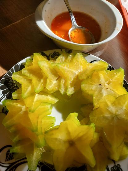 Sliced starfish on plate. Small bowl of nuoc cham with chopped chili sauce sauce is behind the plate