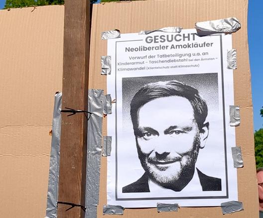 Pappschild von hintern mit einer Art Fahndungsplakat mit einem Foto von Lindner:

Gesucht. Neoliberaler Amokläufer. Vorwurf der Tatbeteiligung u.a. an Kinderarmut - Taschendiebstahl bei den Ärmsten - Klimawandel (Klientelschutz statt Klimaschutz)