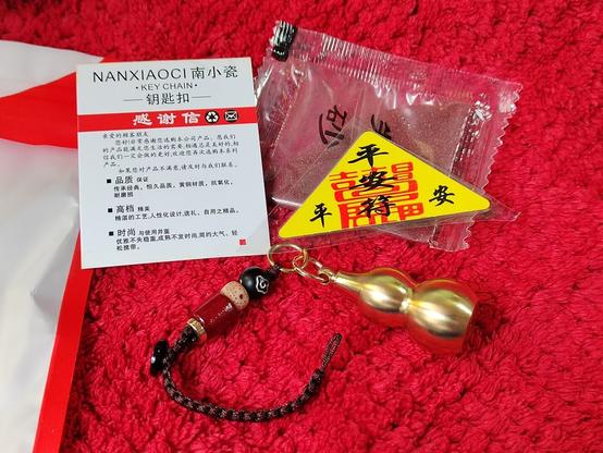 Here are all the contents broken out: a little card explaining what it is, a triangular emblem I've seen in various forms with various things I've purchased of the Daoist flavour.  (I'm too lazy to try to translate it; Daoism has a lot of jargon!)  The charm itself with its braided, buttoned cord so it can be used attached to a key ring, and a little satchel of powdered cinnabar.  (It's not a very high grade of cinnabar, but it is the real deal.)