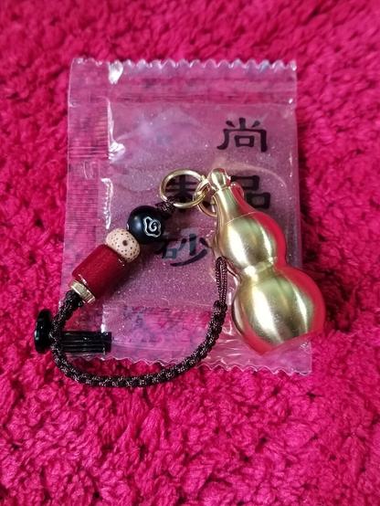 The brass calabash charm sitting atop the satchel of cinnabar.