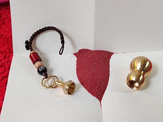 I folded a piece of paper to pour the cinnabar out onto and opened the charm up for display.