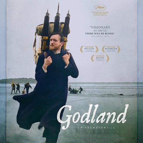 Affiche du film Godland. Un homme habillé en prêtre avec un appareil photo à trépied sur le dos marche le long d'une plage.