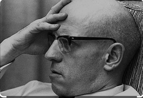Michel Foucault, holding his head in his hands. 

Foucault was a philosopher who wrote a lot about the normalisation of surveillance and how the ultimate goal of the panopticon was that we'd surveil ourselves.