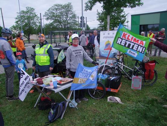 kleines Buffet auf der Wiese der Tram-Wendeschleife mit Demo-Teilnehmenden und Fahnen von Bündnis-Organisationen