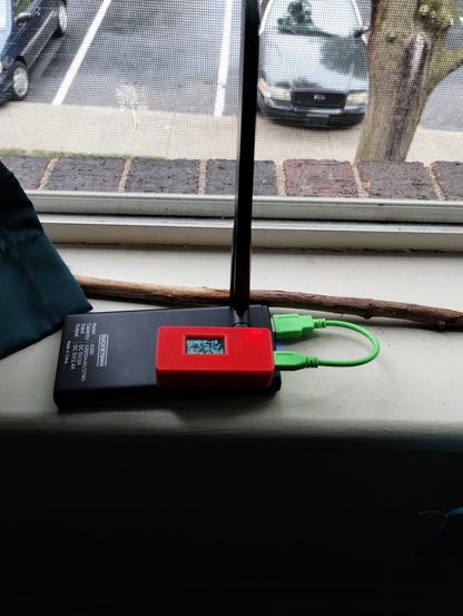 TTGO LoRa board for the LoRa APRS project, sitting in the front window with a battery pack. You can see my Crown Vic CVPI in the background.
