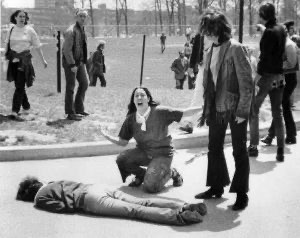 Mary Ann Vecchio screams with her arms outstretched while kneeling over the body of student Jeffery Miller, who was shot through the mouth and killed on May 4, 1970 at Kent State. His blood runs down the pavement behind Vecchio and pools against the curb.