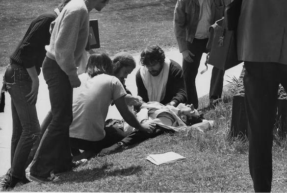 Student John Clearly lays in agony on the grass after being shot by the National Guard at Kent State on May 4, 1970. Several other students kneel over him to provide aid. Clearly would thankfully survive the attack.