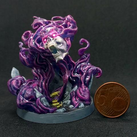 Miniature of a floating skull with glowing hot pink gems for eyes surrounded with swirls of pink/purple smoke. There's a tiny snake coiled up in the rocks on the base.