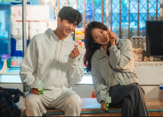 Park Hyung Sik & Park Shin Hye  sitting outside a store in casual clothes with kDrama heart fingers, from the 2024 South Korean drama, "Doctor Slump"
