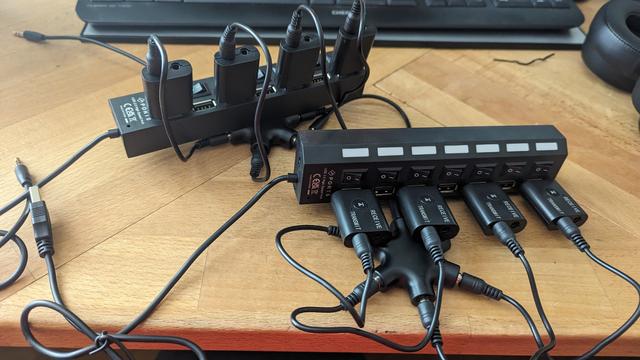 Zwei USB Hubs mit schaltbaren Anschlüssen in denen insgesammt 8 Bluetooth Transmitter sitzen die über einen Sternförmigen Klinken Adapter miteinander in Freiluftverdrahtung verbunden sind.