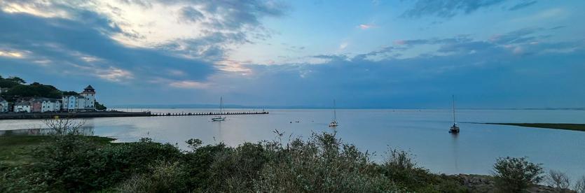 A modern “fishing village” style development, pushing out into the millpond sea, a dramatic sky above.