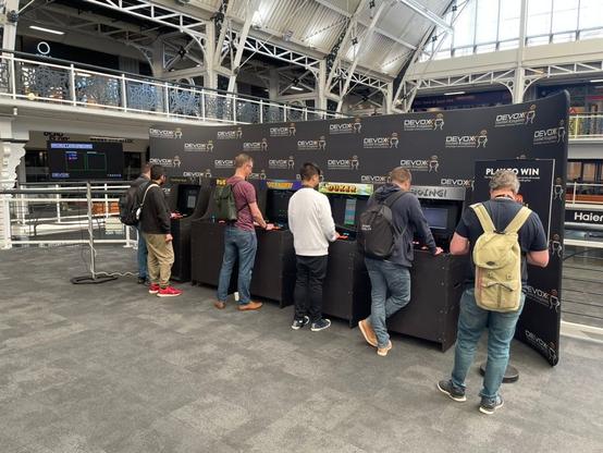 People playing arcade cabinets at Devoxx UK.