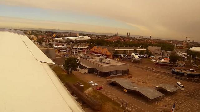 Blick aus dem Fenster eines Kleinflugzeugs im Endanflug auf Piste 16 von Speyer (EDRY): das Technikmuseum mit der Boeing 747 auf dem Podest und die Hinterkante der Tragfläche mit ausgefahrenen Landeklappen sind zu sehen.