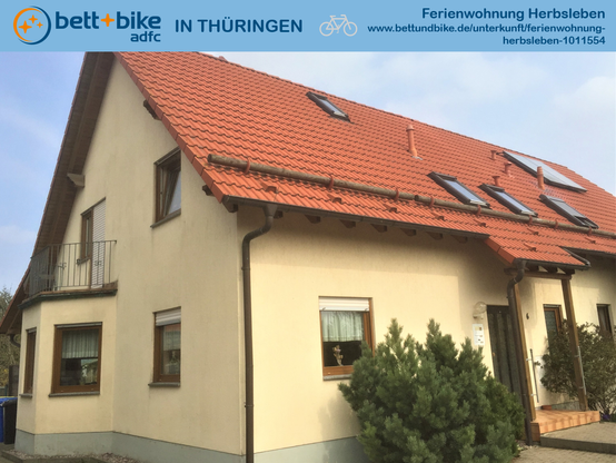 Auf dem Foto zu sehen:
* Nachtaufnahme des Hauses mit der Ferienwohnung:
 - Erdgeschoss mit Erker
 - Dachgeschoss mit Balkon über dem Erker
 - Spitzboden

Oberhalb des Fotos:
* Logos von bett+bike und ADFC Thüringen
* Name und Webseite der Ferienwohnung